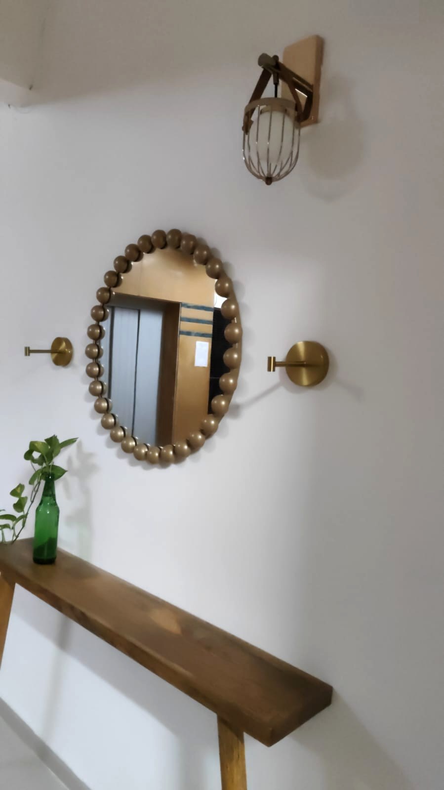 Sculptural rounded mirror with brass lighting
